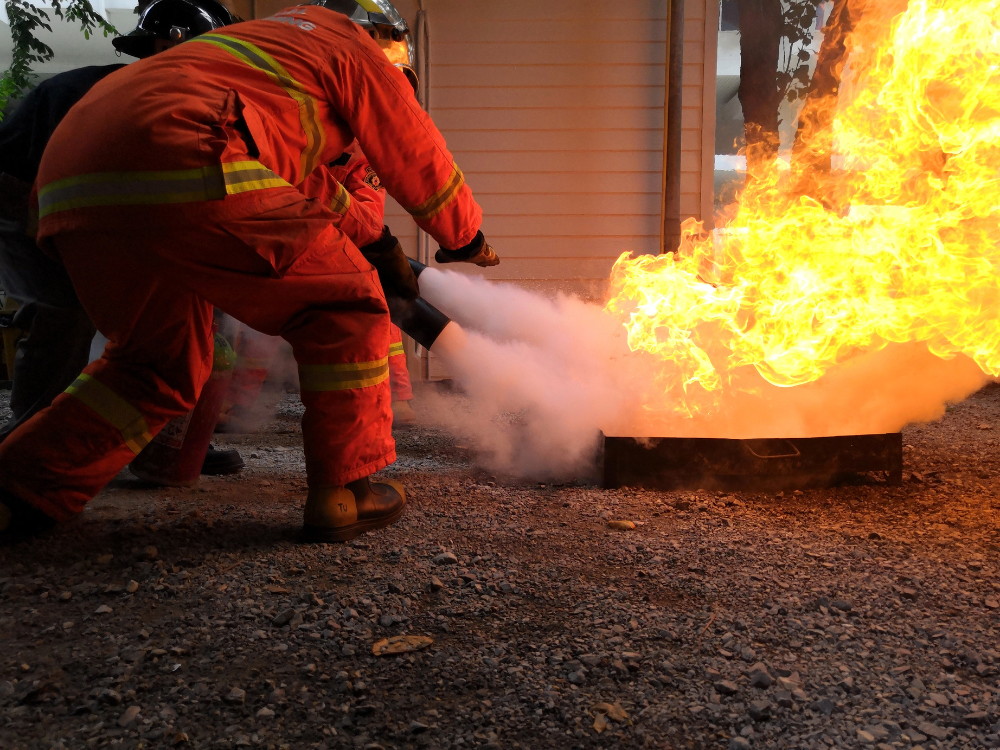 Mit einem Pulverlöscher wird eine Flamme während einer Brandschutzhelferausbildung bekämpft.